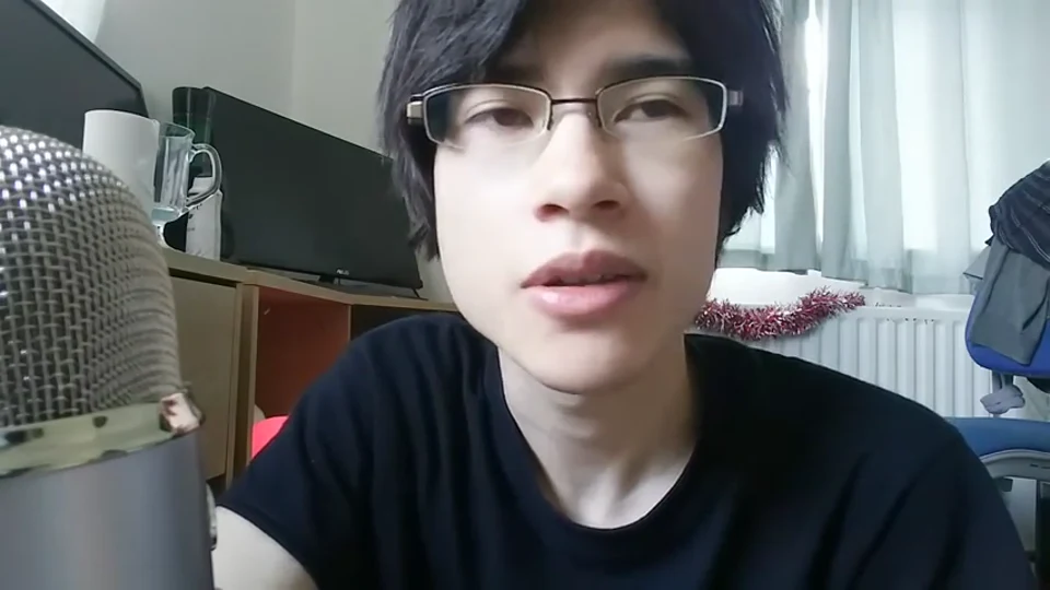Daniel speaking to a camera beside a large microphone in a 2017 video