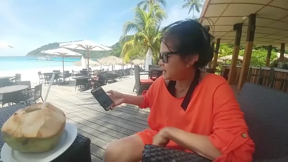 The on-camera participant presented as Daniel's mother, seated outdoors and holding a phone