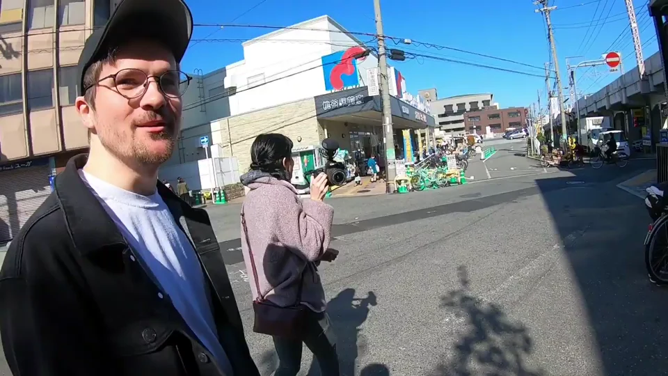 Two people standing outdoors in the archived meeting-labelled video, one holding a camera