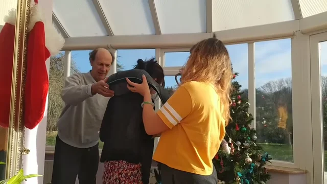 Robert at the left of a Christmas-video frame, standing beside family members near a Christmas tree