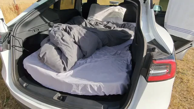 Open rear hatch with mattress, pillows, sheets, and bedding arranged across the rear interior